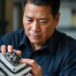 Kaze Mythosのチーフエンジンビルダー、ケンジ・タナカのポートレート。真剣な眼差しでエンジン部品を調べています。